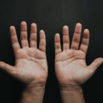 Porównanie rękawiczek medycznych: lateksowe, nitrylowe, winylowe – które wybrać do jakich zastosowań? 2 otwarte dłonie na ciemnym tle